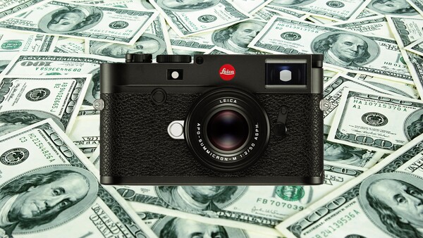 Leica M rangefinder camera with black leather body positioned on a background of US hundred-dollar bills.