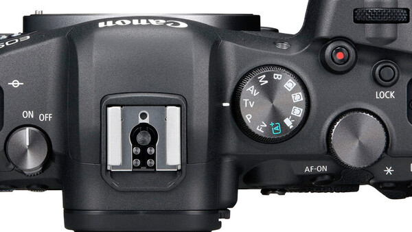 Top view of a mirrorless camera body showing the hot shoe, mode dial, and control buttons.