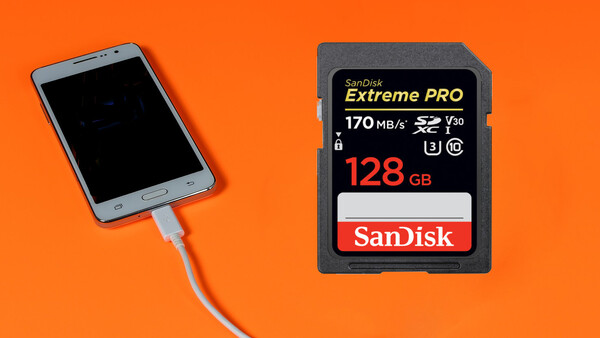 SanDisk Extreme PRO 128GB SD card next to a smartphone connected via USB cable.