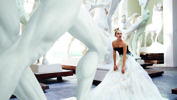 Bride in white gown posed among large white sculptural forms in modern gallery setting.