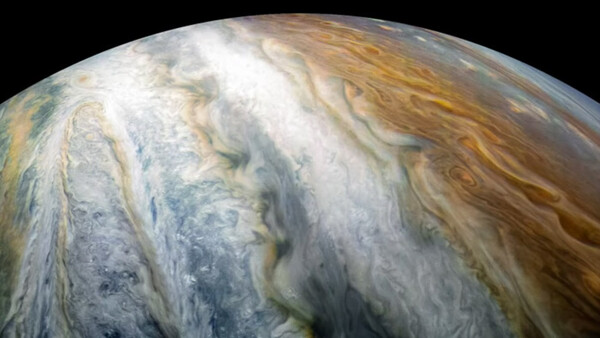 Close-up of Jupiter's cloud bands showing swirling atmospheric patterns in white, tan, and gray tones.