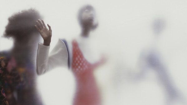 Silhouetted figures with raised hands in soft focus against a bright, hazy background.