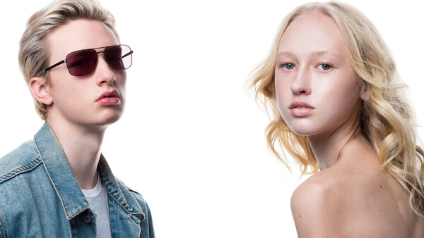 Two blonde individuals with neutral expressions against white background, one wearing sunglasses and denim jacket.