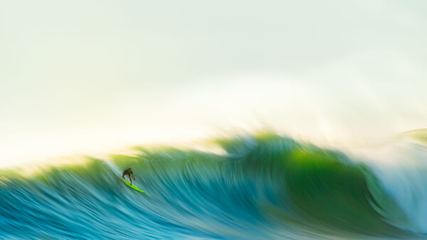 A surfer riding inside a barrel on a large ocean wave with dynamic motion blur effect.