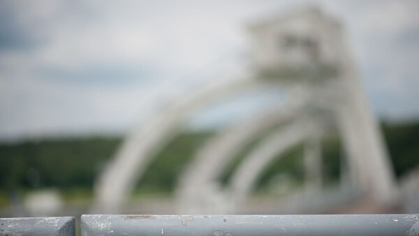 White architectural structure with curved forms blurred in background, sharp metal railing in foreground.