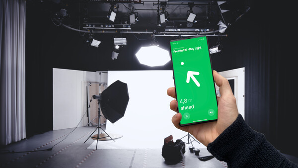 Hand holding green smartphone displaying navigation app with directional arrow in professional studio setting.
