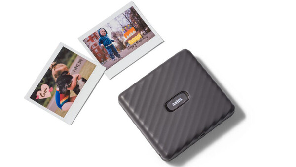 Portable photo printer with two instant prints displayed above it on white background.