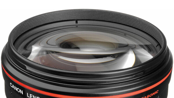 Close-up of a Canon lens showing internal glass elements and red accent ring.