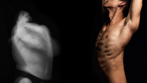 Shirtless male figure with defined abdominal muscles against black background, arm raised above head.