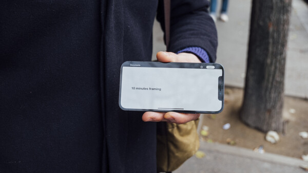 Person in dark clothing holding a smartphone displaying a loading screen with text.