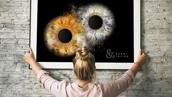 Large framed print displaying two close-up human irises—one golden-brown, one blue-gray—against black background.