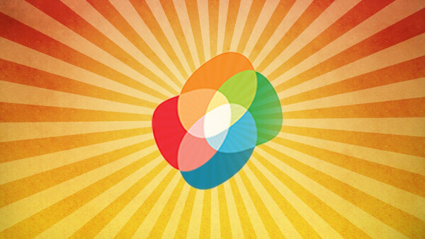 Illustration of overlapping colored circles arranged in a pinwheel pattern with a white center, radiating against a sunburst background.