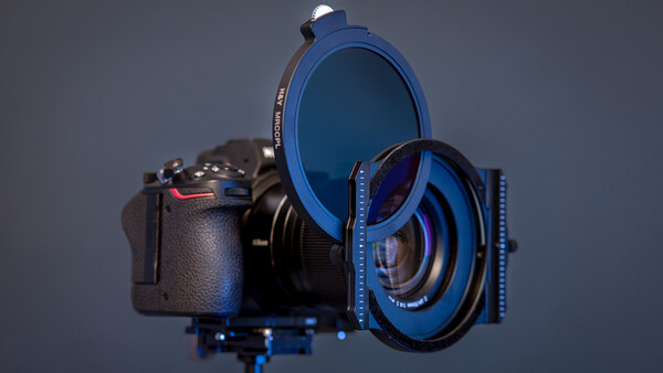 Camera with blue filter system and lens attachments arranged on neutral background.