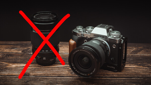 Vintage film camera next to a rejected zoom lens with red X mark on wooden surface.