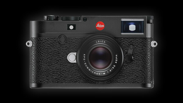 Leica M rangefinder camera with black leather body and 50mm lens against dark background.
