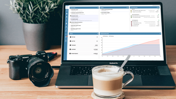 Sony mirrorless camera and laptop displaying analytics dashboard on wooden desk workspace.