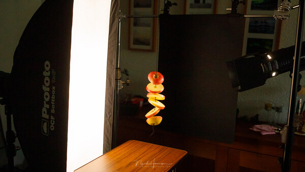 Studio product photography setup with stacked citrus fruits lit by a large softbox and spotlight.