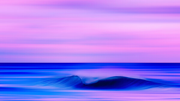 Ocean wave with motion blur against a vibrant pink and purple twilight sky.