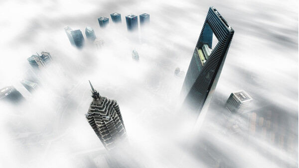 Skyscrapers emerging from thick fog and clouds in an urban cityscape.