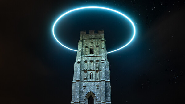 Stone tower on a grassy hill illuminated by a bright cyan neon ring hovering above it against a dark night sky.