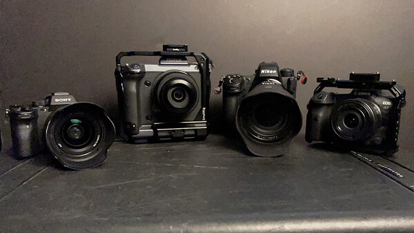 Four digital cameras of varying sizes arranged in a line on a dark surface.