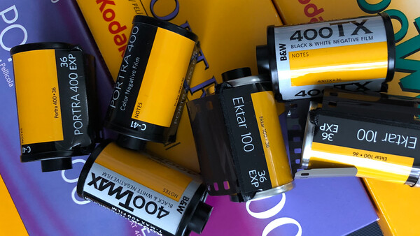 Collection of expired film rolls including Kodak Portra and Ektar stocks arranged on colorful background.