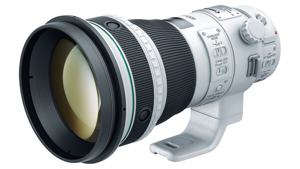 White and black telephoto lens with extended barrel and control rings mounted on camera body.