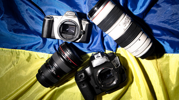 Canon DSLR camera with interchangeable lenses arranged on blue and yellow fabric backdrop.