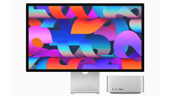 Desktop monitor displaying vibrant abstract geometric shapes in magenta, cyan, orange, and blue.