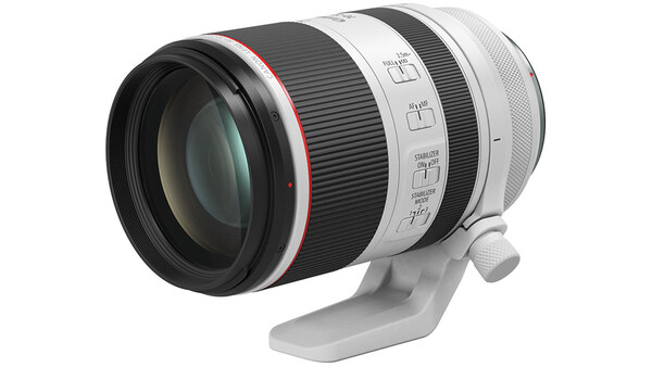 White and black telephoto lens with red accent ring mounted on a white tripod collar.