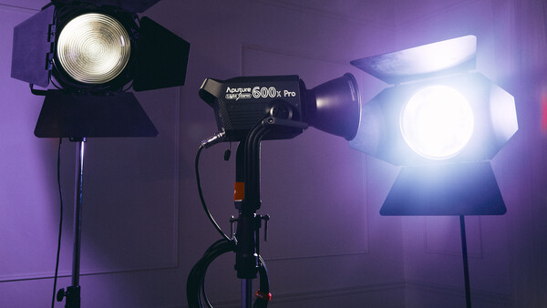 Three professional studio lights with Fresnel lenses positioned in a purple-lit photography setup.