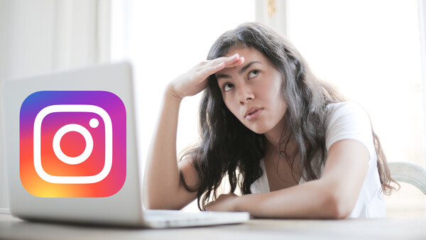 Woman at desk with hand to forehead looking at laptop displaying Instagram logo.