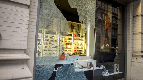 Storefront window display at night with illuminated product shelves and interior lighting reflecting off glass.