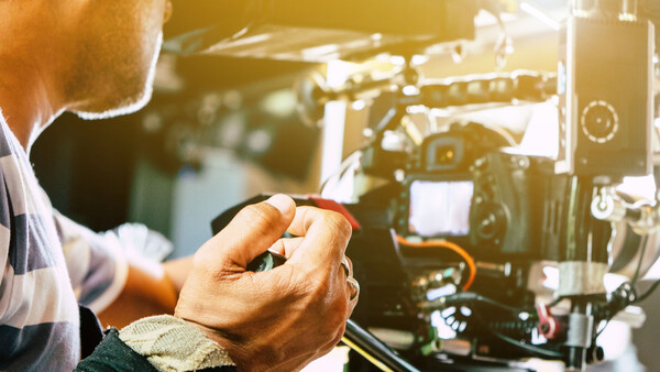 Filmmaker's hands adjusting controls on a cinema camera during production setup.