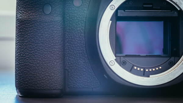 Mirrorless camera body with open sensor mount showing internal mirror and shutter mechanism.