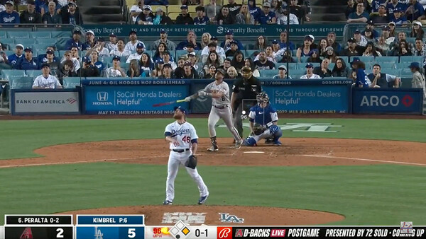 Baseball pitcher in white uniform mid-delivery during professional game with crowded stadium stands in background.