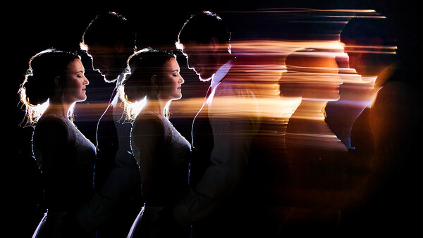 Profile silhouettes of a woman with glowing light trails and motion blur effects against a dark background.