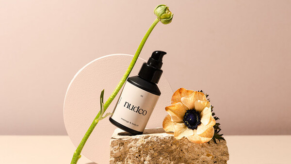 Cosmetic product photography featuring a spray bottle with natural elements on textured stone.