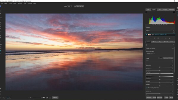Beach at sunset with golden and pink light reflecting on wet sand and calm ocean water.
