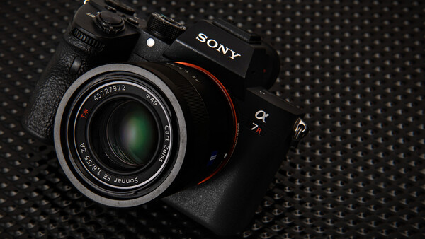 Sony mirrorless camera with attached prime lens on textured dark surface.