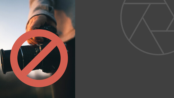 A photographer holding a telephoto lens with a red prohibition symbol overlaid on the image.