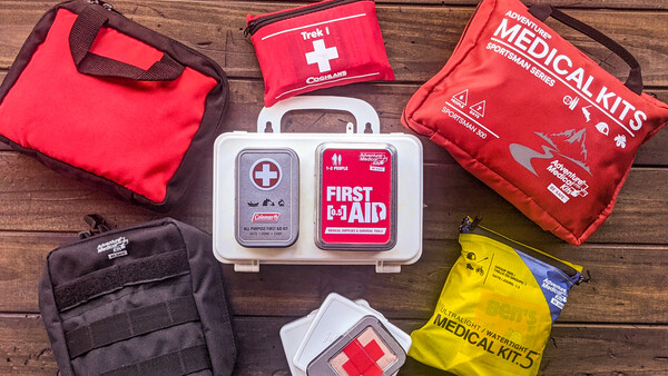 Collection of first aid and medical kits arranged on wooden surface.