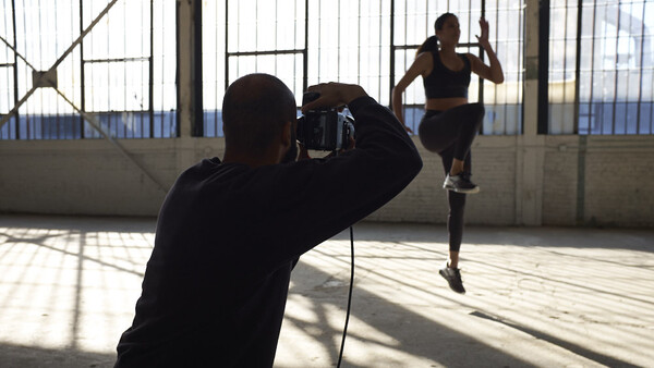 Photographer shooting a runner in motion on a rooftop with industrial architecture and natural window light.