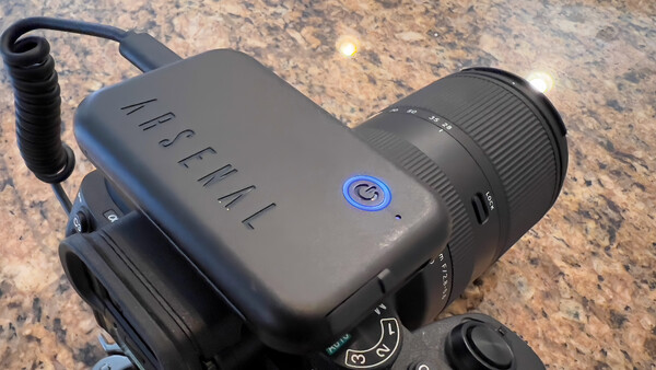Handheld camera with microphone attachment mounted on textured stone surface.
