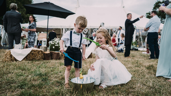 Two young children playing in a sandbox at an outdoor garden wedding ceremony.