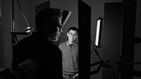 Two people working with professional lighting equipment in a studio setting.