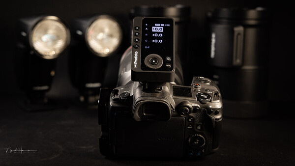 Professional camera with wireless flash trigger mounted on hot shoe, positioned in front of studio lighting setup.