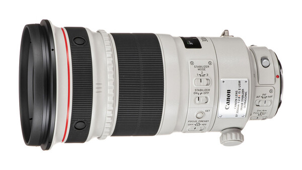 Canon telephoto lens with white barrel, control rings, and focus switches displayed against white background.
