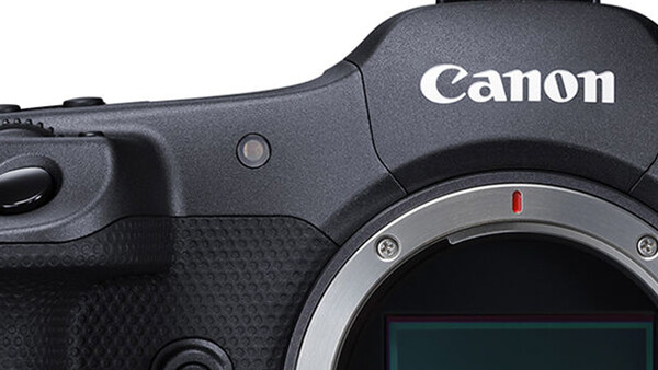 Close-up of Canon camera body showing grip, shutter button, and lens mount with red dot alignment marker.