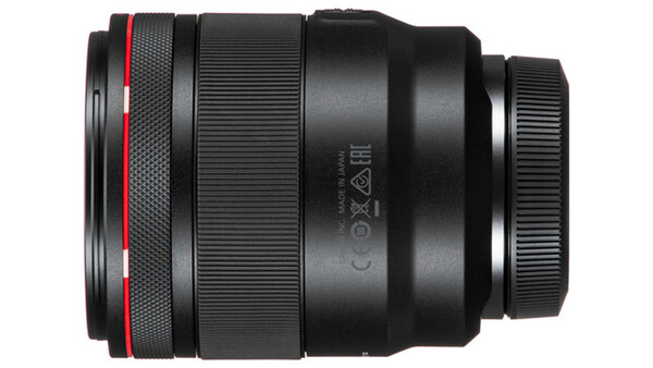Black camera lens with red accent ring and visible optical elements viewed from the side.